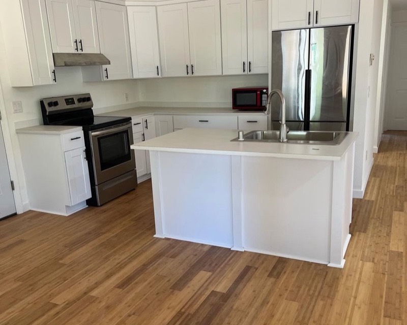 Kitchen remodel — white shaker cabinets, quartz island, and hardwood floors in Poulsbo